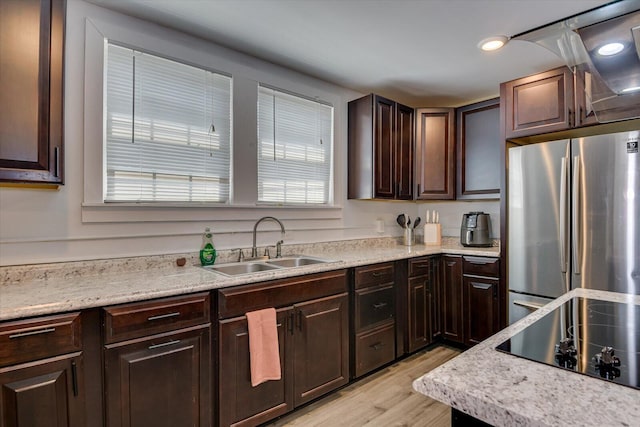 kitchen with dark brown cabinetry, sink, light hardwood / wood-style flooring, stainless steel fridge, and black electric stovetop