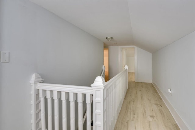 hallway featuring light wood-type flooring and vaulted ceiling