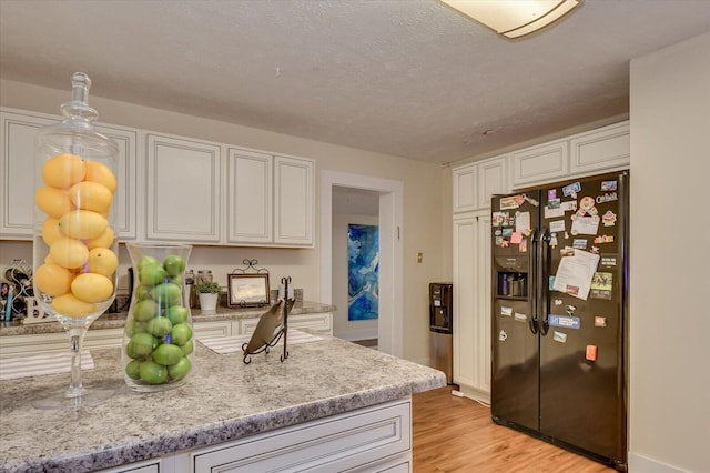 kitchen featuring white cabinetry, refrigerator with ice dispenser, and light hardwood / wood-style floors