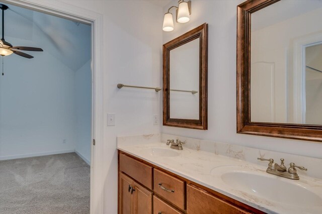 full bathroom with double vanity, a ceiling fan, baseboards, and a sink