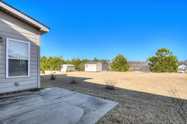 view of yard with an outbuilding, a storage unit, and a patio area