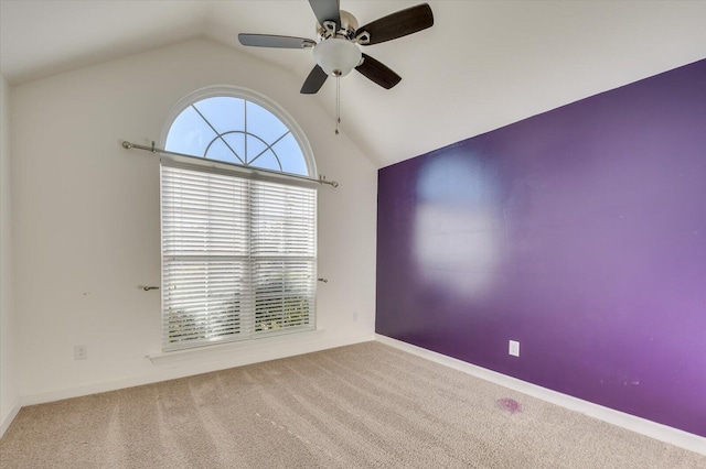 carpeted empty room with lofted ceiling, baseboards, and ceiling fan