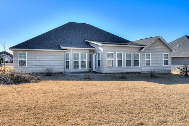 back of property with a yard and roof with shingles