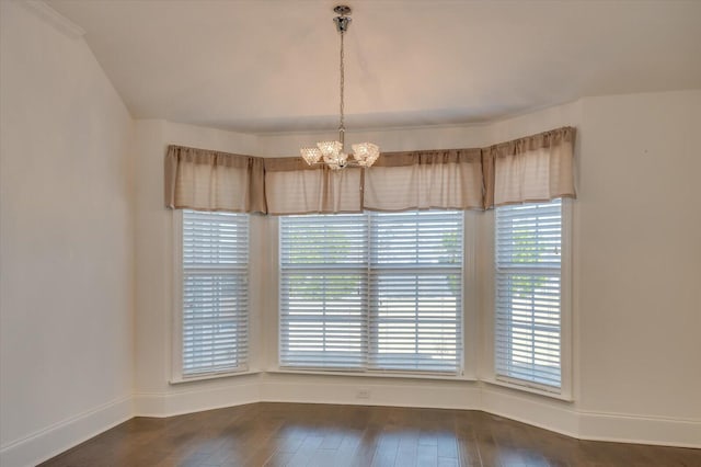 unfurnished dining area featuring a notable chandelier, baseboards, and hardwood / wood-style flooring