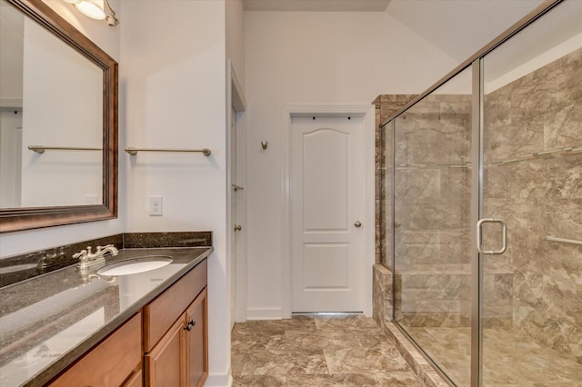 bathroom with vanity, a shower stall, and vaulted ceiling