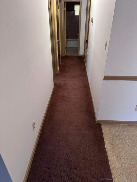 hall featuring dark colored carpet