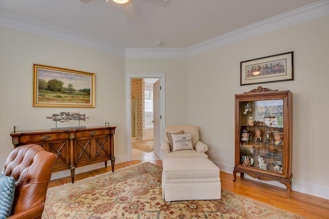 living area with light hardwood / wood-style floors, ceiling fan, and crown molding