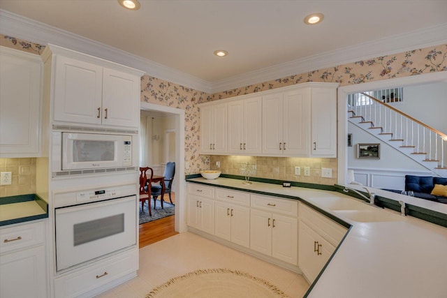 kitchen featuring tasteful backsplash, ornamental molding, white appliances, sink, and white cabinets