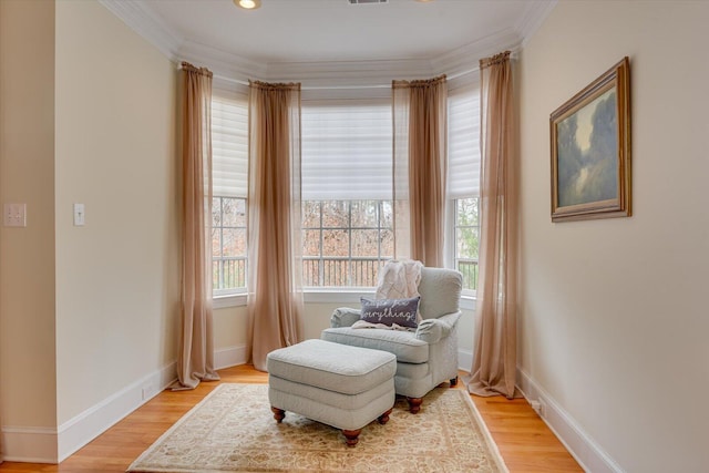 living area with plenty of natural light, light wood-type flooring, and ornamental molding