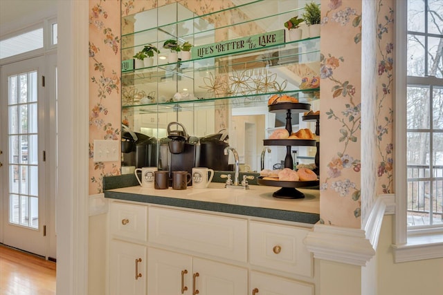 bar featuring white cabinets, light hardwood / wood-style floors, and sink