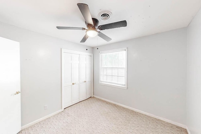 unfurnished bedroom featuring ceiling fan, a closet, and light colored carpet