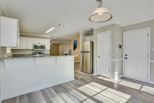 kitchen featuring white cabinets, kitchen peninsula, ornamental molding, and appliances with stainless steel finishes