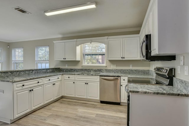 kitchen with light stone countertops, appliances with stainless steel finishes, white cabinetry, and a healthy amount of sunlight