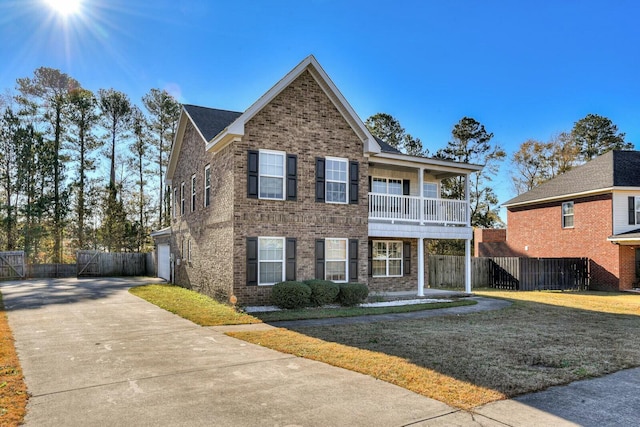 front facade featuring a balcony, a front yard, and a garage