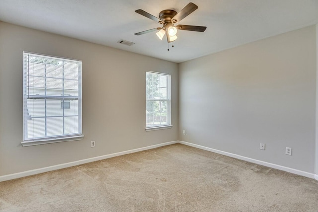 empty room with light carpet, ceiling fan, and a healthy amount of sunlight