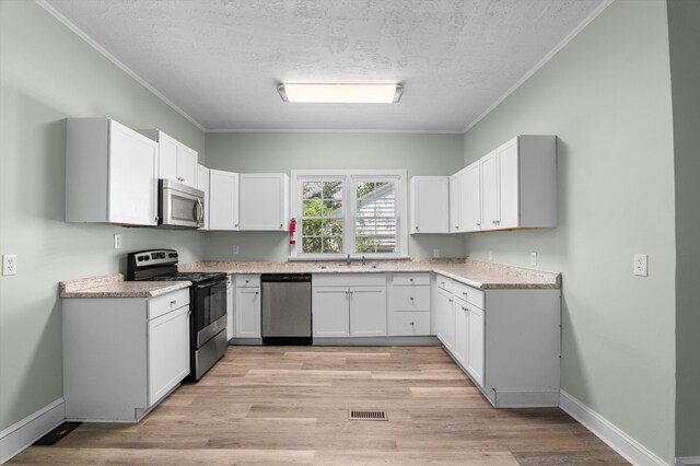 1940 Telfair St, Augusta, GA 30904 - kitchen with stainless steel appliances, ornamental molding, a textured ceiling, light wood-style floors, and baseboards