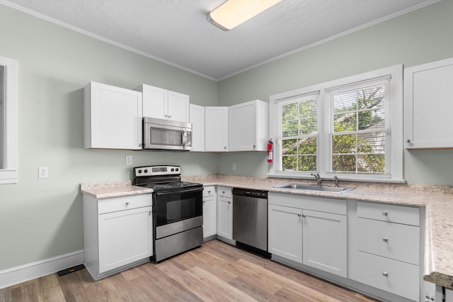 1940 Telfair St, Augusta, GA 30904 - kitchen featuring appliances with stainless steel finishes, a sink, light wood-style floors, ornamental molding, and white cabinets