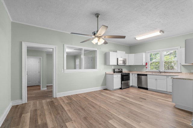 1940 Telfair St, Augusta, GA 30904 - kitchen featuring stainless steel appliances, a textured ceiling, light countertops, crown molding, and light wood-style floors