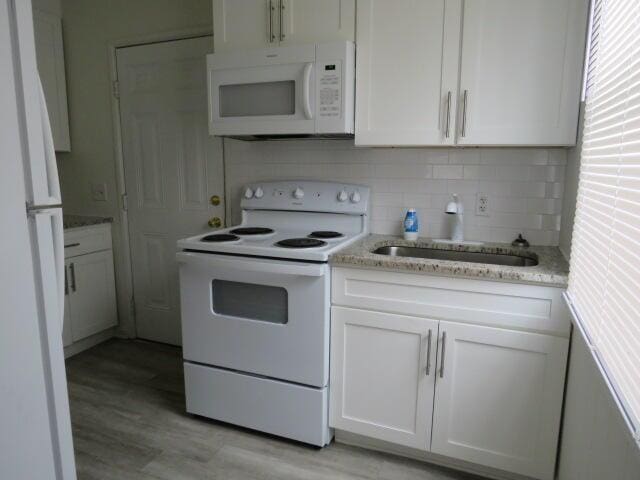 2480 Miles Ave, Augusta, GA 30906 - kitchen with white appliances, white cabinets, light wood finished floors, and tasteful backsplash