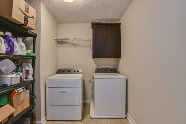 washroom featuring cabinets, light tile patterned floors, a textured ceiling, and washing machine and clothes dryer