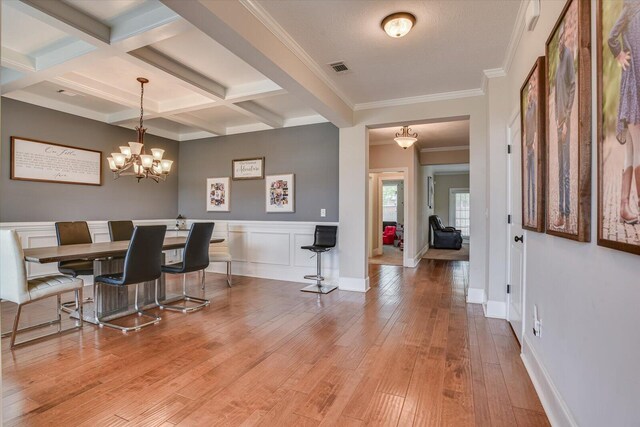 dining area featuring beamed ceiling, light hardwood / wood-style flooring, coffered ceiling, and a notable chandelier