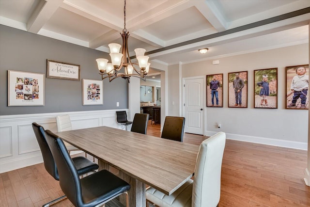 dining space with beam ceiling, a chandelier, wood-type flooring, and ornamental molding