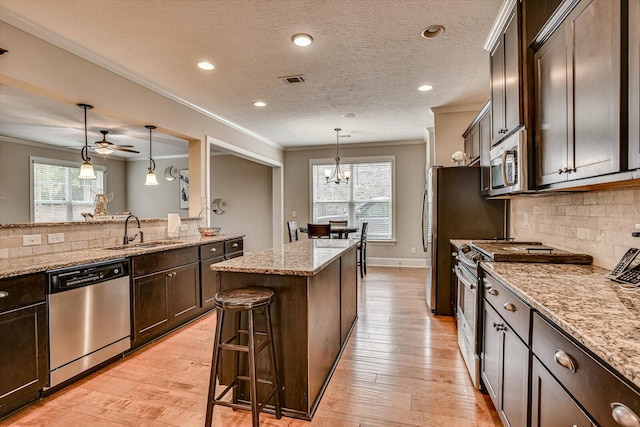 kitchen with a kitchen breakfast bar, crown molding, sink, and appliances with stainless steel finishes