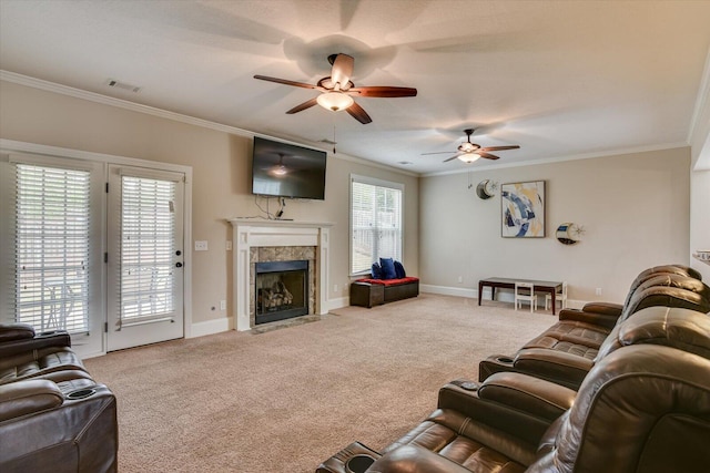 carpeted living room with a tile fireplace, a wealth of natural light, ornamental molding, and ceiling fan