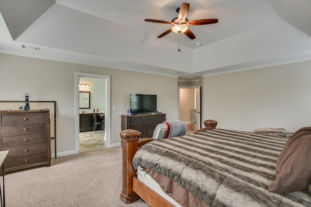 bedroom featuring ensuite bath, ceiling fan, ornamental molding, a tray ceiling, and light colored carpet