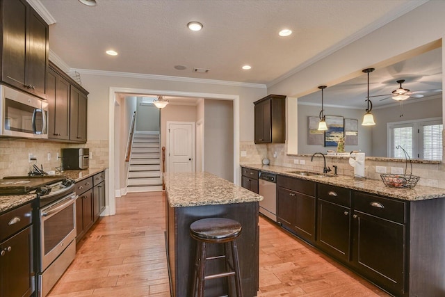 kitchen featuring crown molding, sink, a kitchen island, and stainless steel appliances