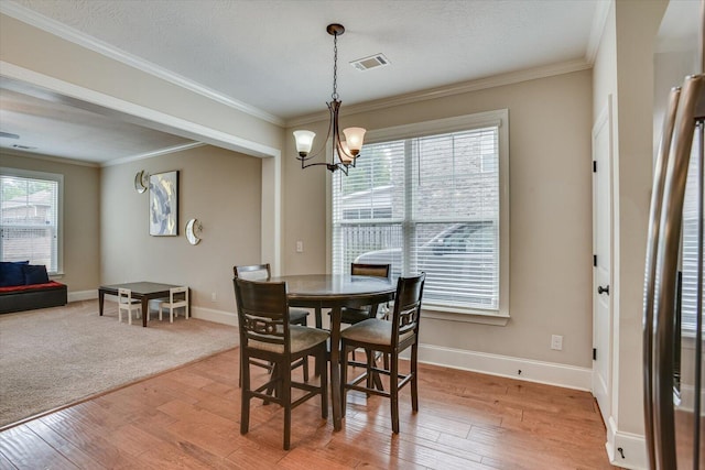 dining space with plenty of natural light, crown molding, and an inviting chandelier