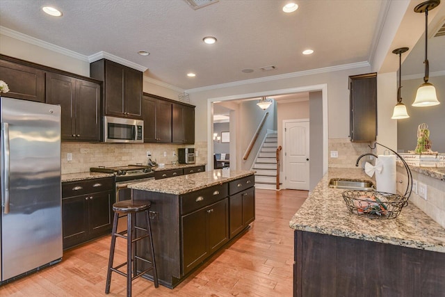 kitchen featuring decorative backsplash, dark brown cabinets, stainless steel appliances, sink, and hanging light fixtures