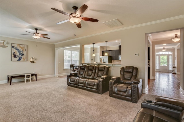 living room featuring carpet flooring, ceiling fan, and ornamental molding