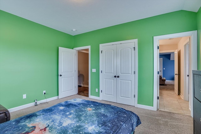 bedroom featuring lofted ceiling, light carpet, and a closet