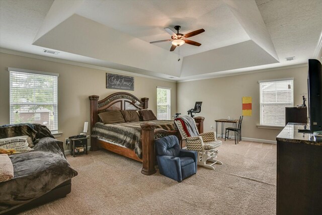 carpeted bedroom featuring a raised ceiling, ceiling fan, and ornamental molding