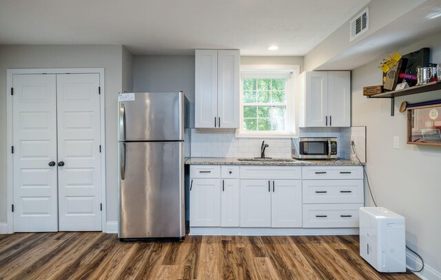 kitchen with white cabinets, decorative backsplash, sink, and stainless steel appliances