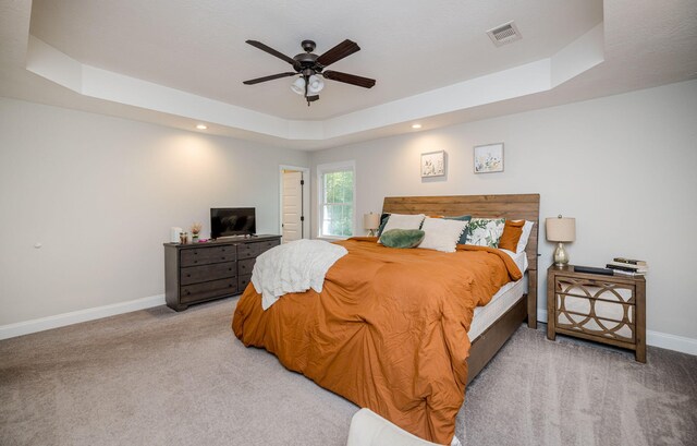 carpeted bedroom featuring a raised ceiling and ceiling fan