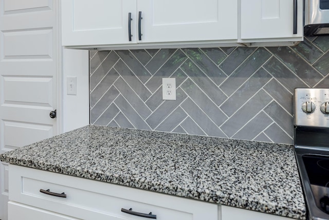 kitchen featuring tasteful backsplash, white cabinets, and stone countertops