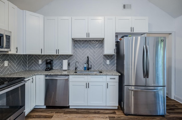 kitchen featuring light stone counters, stainless steel appliances, sink, white cabinets, and lofted ceiling