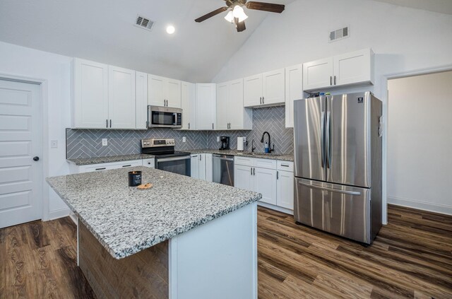 kitchen with white cabinets, a kitchen island, appliances with stainless steel finishes, and tasteful backsplash