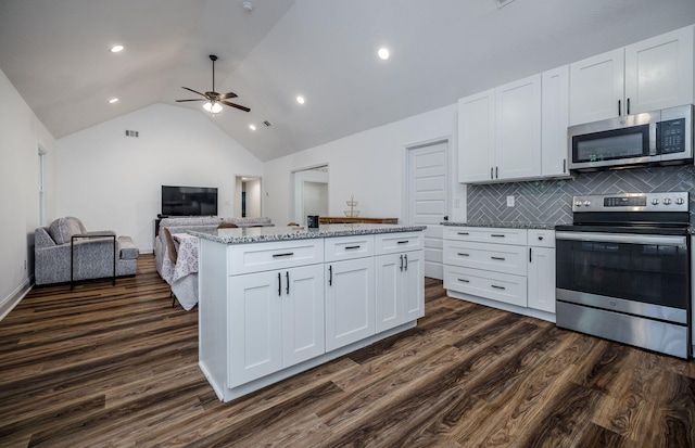 kitchen featuring decorative backsplash, light stone countertops, stainless steel appliances, a center island, and white cabinetry