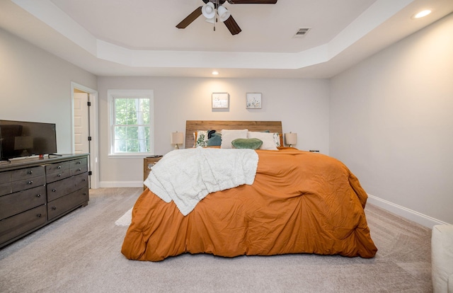 bedroom featuring ceiling fan, light carpet, and a tray ceiling