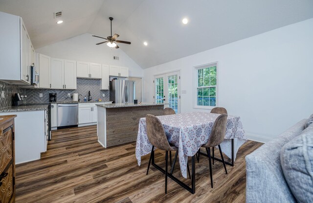 dining room featuring ceiling fan, sink, high vaulted ceiling, and dark wood-type flooring