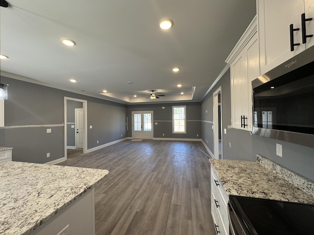 kitchen with dark wood-style floors, crown molding, stainless steel microwave, white cabinets, and baseboards