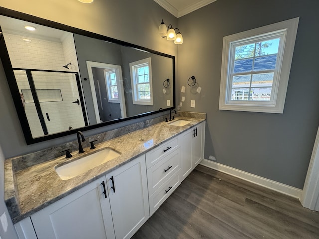 full bathroom featuring crown molding, wood finished floors, a sink, and a shower stall