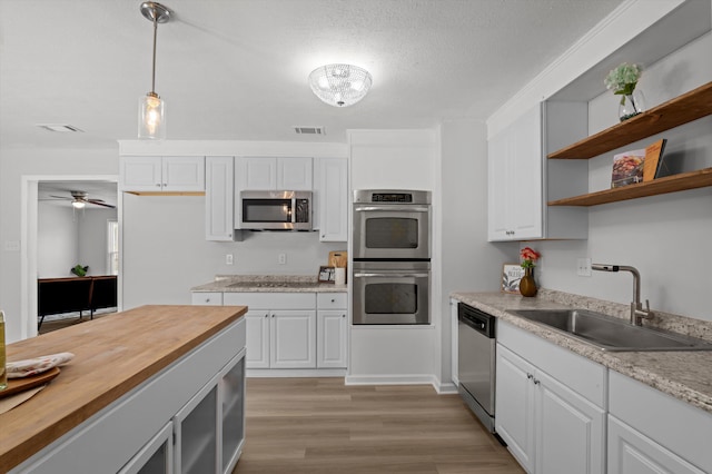 4221 Cap Chat St, Hephzibah, GA 30815 - kitchen with appliances with stainless steel finishes, wood counters, pendant lighting, light wood finished floors, and white cabinetry