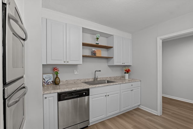 4221 Cap Chat St, Hephzibah, GA 30815 - kitchen featuring stainless steel appliances, light wood-type flooring, white cabinets, open shelves, and a textured ceiling