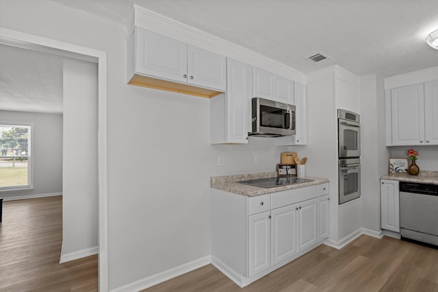 4221 Cap Chat St, Hephzibah, GA 30815 - kitchen featuring stainless steel appliances, light wood-style flooring, white cabinetry, and a textured ceiling
