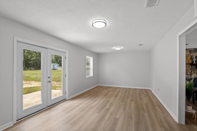 4221 Cap Chat St, Hephzibah, GA 30815 - unfurnished room featuring light wood finished floors, french doors, a textured ceiling, and a fireplace