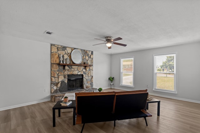 4221 Cap Chat St, Hephzibah, GA 30815 - living room featuring a textured ceiling, wood finished floors, a stone fireplace, and a ceiling fan